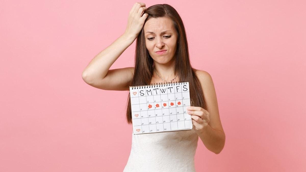 Woman reviewing a menstrual calendar while experiencing an irregular cycle